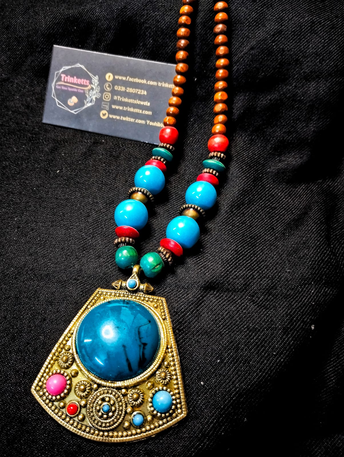 Antique-Style Maala Necklace with Brown Wooden Beads, Red and Blue Plastic Beads, and Brass-Colored Pendant Adorned with Blue Stones