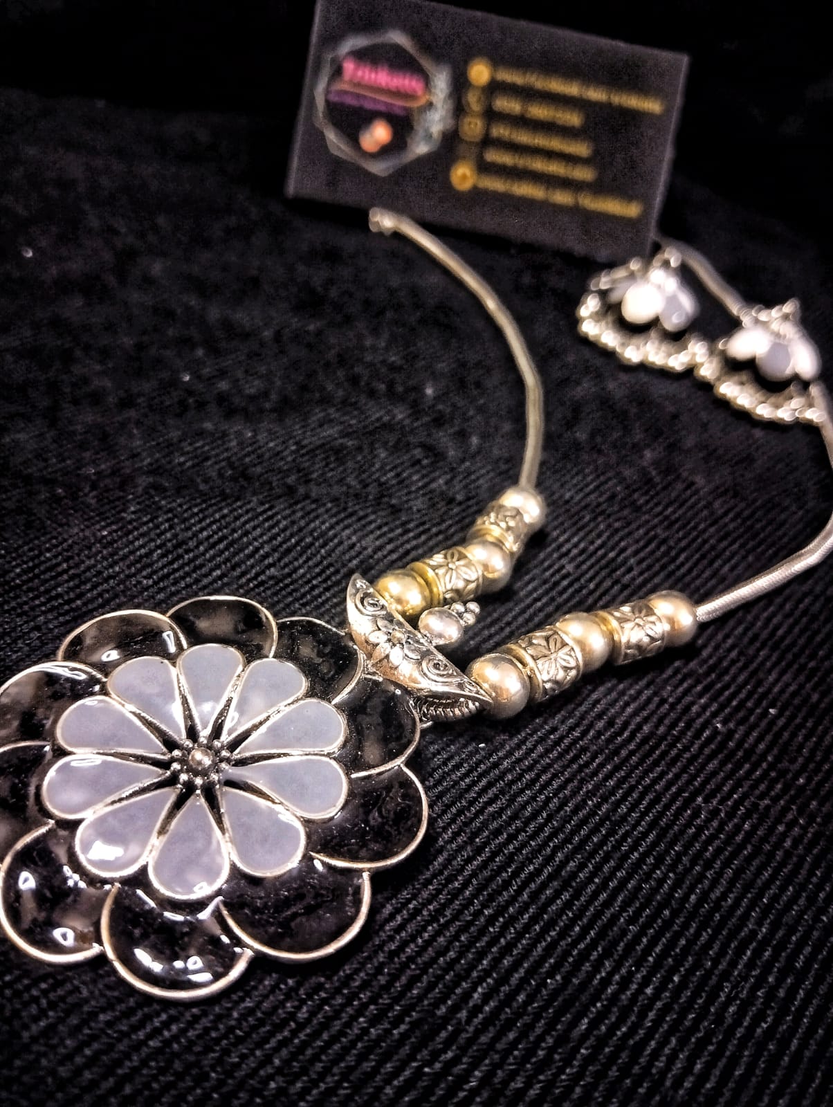 A black Floral Meenakaari Jewelry Set in black and grey Meena Kaari design, accompanied by matching Meena Karai jhumkis (dangling earrings) in black and grey, featuring attached ghungroos (small bells). The pendant hangs on an oxidized silver chain with an S hook closure."