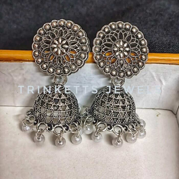 Trinketts Silver Oxidized Jhumkis with Geometric Jhumki Plate Design and Elegant White Beads - 1.5 Inches. Unique circular and intricate top design with brick-style geometric patterns on the jhumki plate. Perfect blend of traditional and contemporary style. Price: Rs. 300.