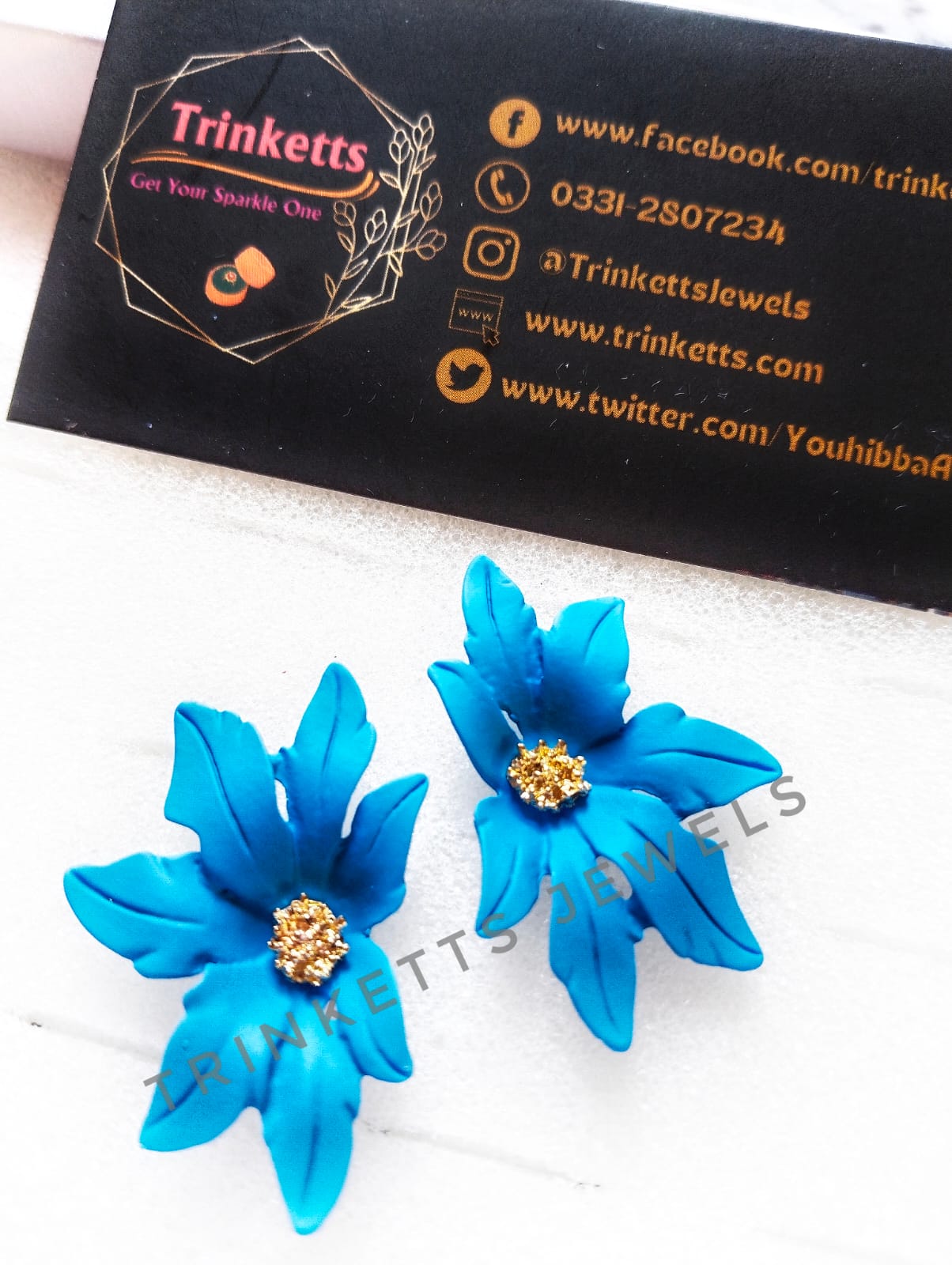 Handcrafted sky blue clay floral studs with leafy petals and a center rhinestone in copper. Artisanal jewelry, blending nature-inspired design with the warmth of clay craftsmanship.