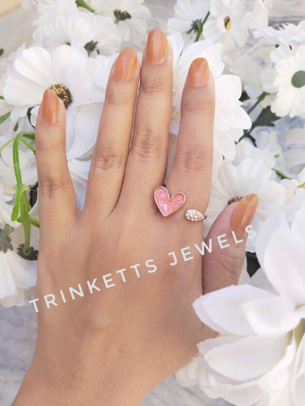 Adjustable tea pink heart ring with glittery marble effect stone framed in gold polish on one end and zircon stones in an oval shape on the other. Elegant and versatile, perfect for adding a touch of glamour to any outfit.