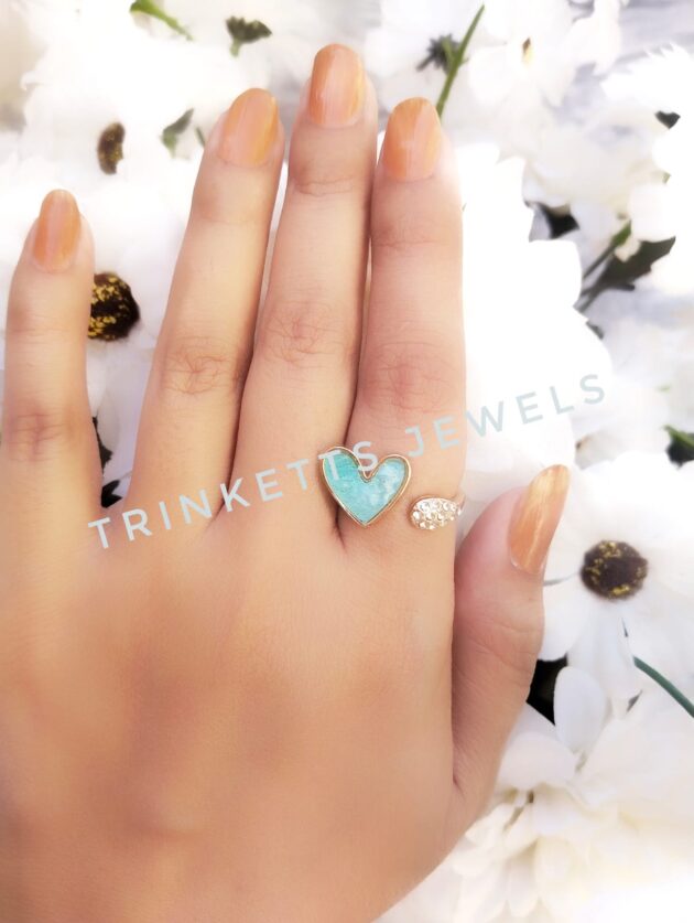Adjustable ice blue heart ring with glittery marble effect stone framed in gold polish on one end and zircon stones in an oval shape on the other. Elegant and versatile, perfect for adding a touch of glamour to any outfit.