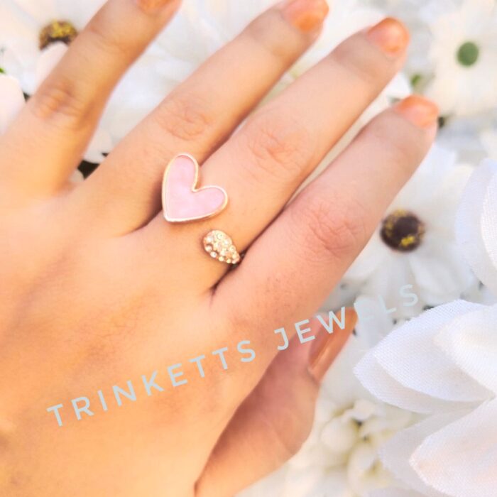 Adjustable baby pink heart ring with glittery marble effect stone framed in gold polish on one end and zircon stones in an oval shape on the other. Elegant and versatile, perfect for adding a touch of glamour to any outfit.