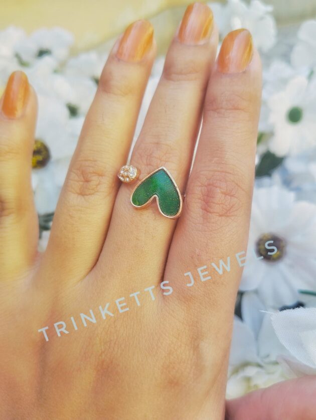 Adjustable green heart ring with glittery marble effect stone framed in gold polish on one end and zircon stones in an oval shape on the other. Elegant and versatile, perfect for adding a touch of glamour to any outfit.