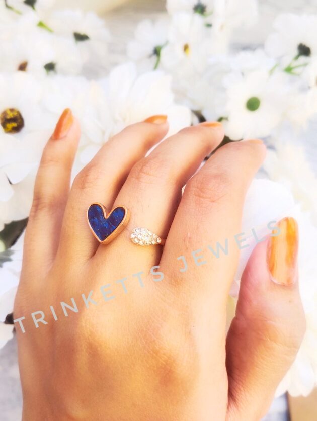 Adjustable blue heart ring with glittery marble effect stone framed in gold polish on one end and zircon stones in an oval shape on the other. Elegant and versatile, perfect for adding a touch of glamour to any outfit.