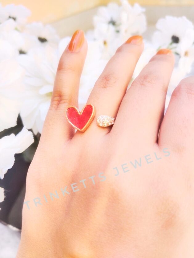 Adjustable red heart ring with glittery marble effect stone framed in gold polish on one end and zircon stones in an oval shape on the other. Elegant and versatile, perfect for adding a touch of glamour to any outfit.