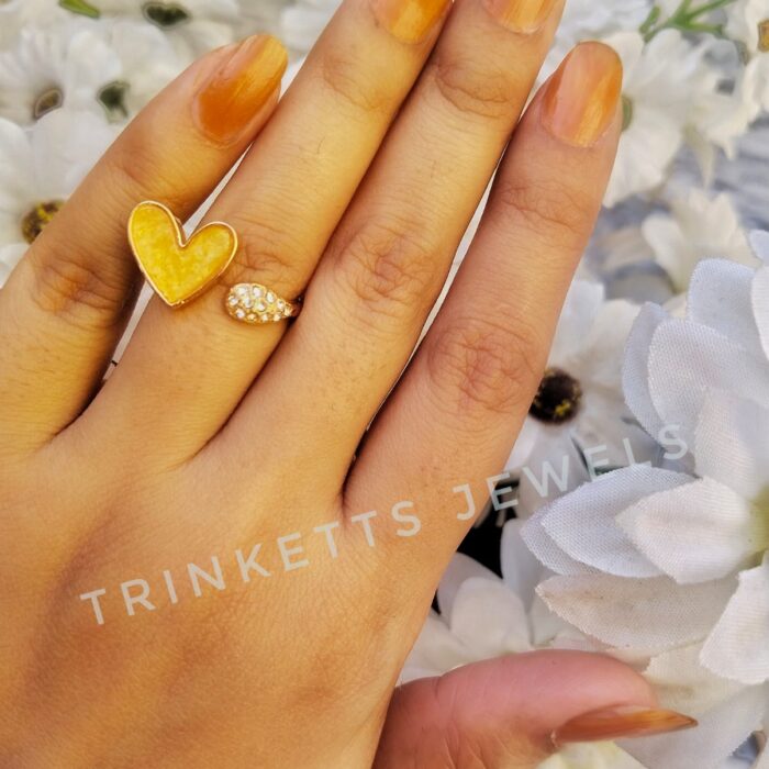 Adjustable golden yellow heart ring with glittery marble effect stone framed in gold polish on one end and zircon stones in an oval shape on the other. Elegant and versatile, perfect for adding a touch of glamour to any outfit.